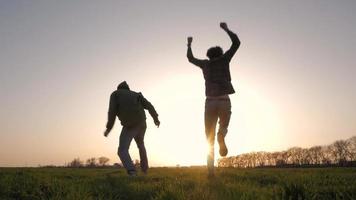 Silhouette von zwei jungen Leuten, die auf den Feldern laufen video