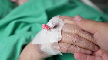 Person visiting grandmother in a hospital and stroking her hand
