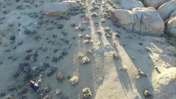 Toma aérea de un joven mochilero con su perro en un desierto montañoso.