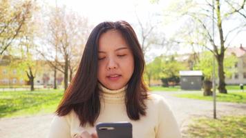 mujer asiática cara feliz y caminar y usar su teléfono inteligente