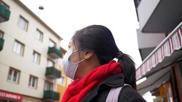 mujer asiática con máscara, salir y mirar alrededor de un pequeño pueblo. Excelente ambiente y hermosos edificios. covid 19 en temporada de invierno, protección