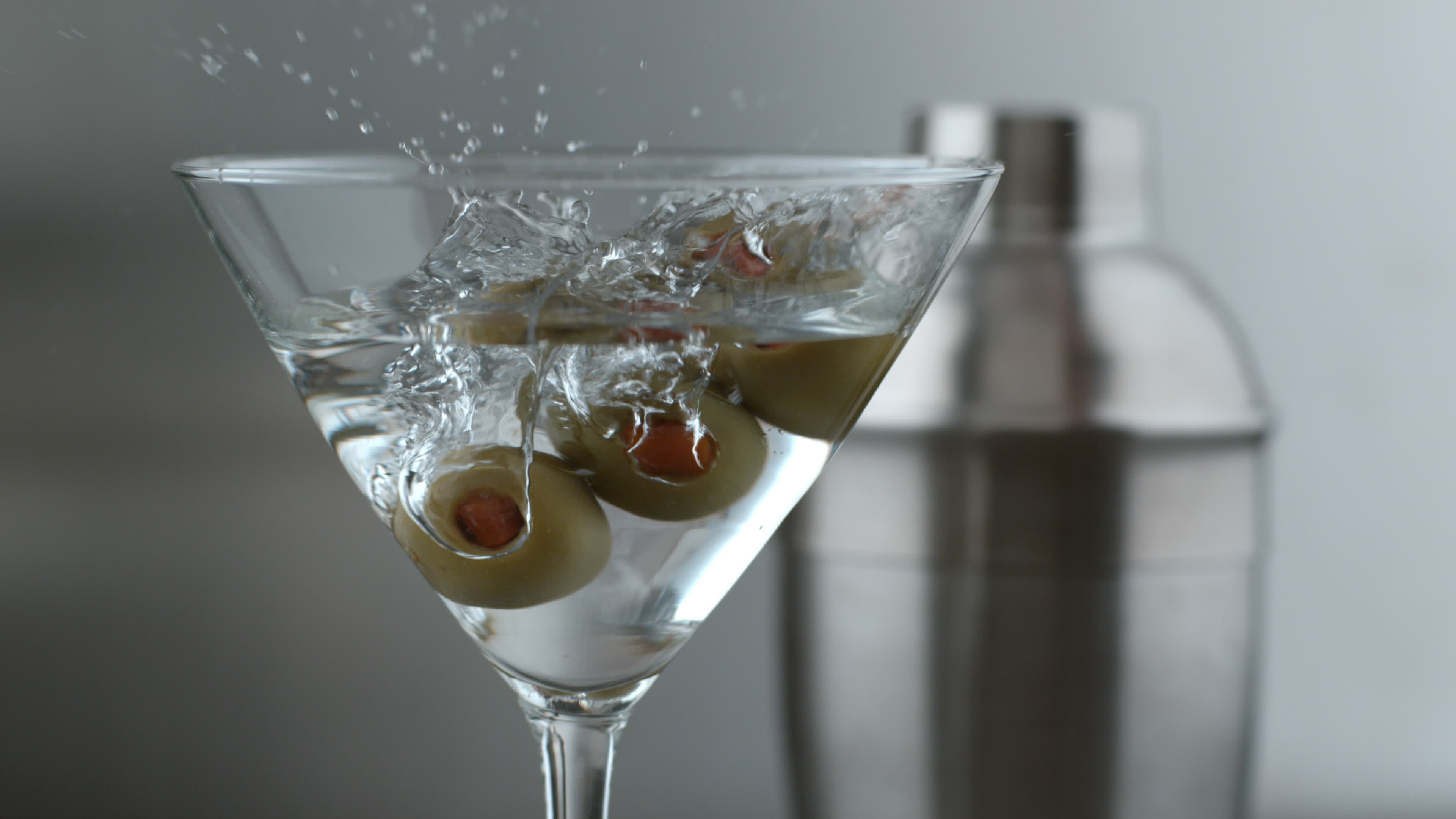 Slow motion shot of olives splashing into martini. shot on Phantom Flex