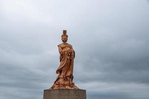 La estatua de bronce de la diosa religiosa china en tiempo nublado foto