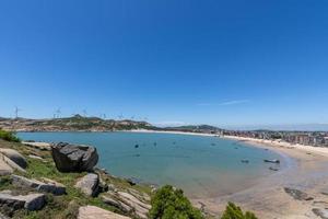 párese alto y observe el paisaje marino bajo el cielo azul, el agua azul, las olas blancas y las rocas negras foto