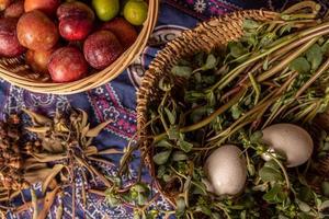 The eggs and other fruits and vegetables in the basket are on the wood grain table photo