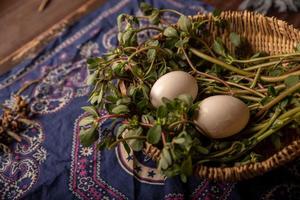 The eggs and other fruits and vegetables in the basket are on the wood grain table photo