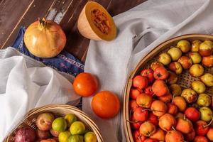 Many colors and varieties of fruit are either on the plate or scattered on the wooden table photo