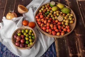 Many colors and varieties of fruit are either on the plate or scattered on the wooden table photo