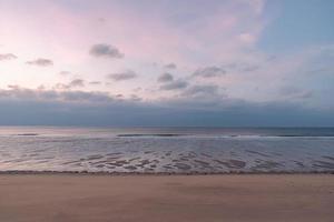 In the early morning by the sea, the sky and the beach are slightly red photo