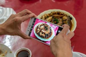 A man is taking pictures with a mobile phone in his hand photo