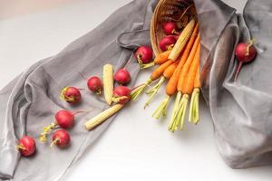 The red and orange radishes are on the white cloth photo