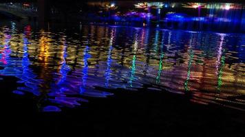 por la noche, el arroyo refleja las luces de colores en el puente foto