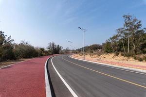 The asphalt road leading to the distance is under the blue sky photo