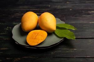 Cut and complete mangoes on a plate in a dark environment photo