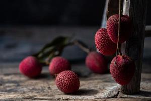 Litchi is placed in a wooden plate, peeled or unopened, on a dark wood grain table photo