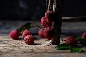 Litchi is placed in a wooden plate, peeled or unopened, on a dark wood grain table photo