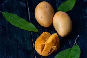 Cut and intact mangoes in the dark background photo