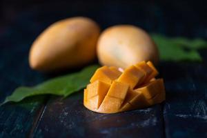 Cut and intact mangoes in the dark background photo