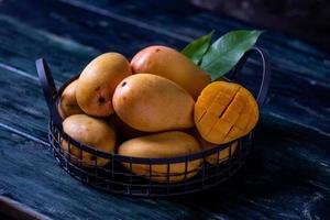 Cut and intact mangoes in the dark background photo