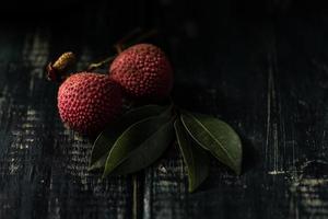 El litchi se coloca en un plato de madera, pelado o sin abrir, sobre una mesa de madera oscura. foto