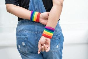 dama asiática con pulseras con la bandera del arco iris, símbolo del mes del orgullo lgbt celebrar anualmente en junio social de gays, lesbianas, bisexuales, transgénero, derechos humanos foto