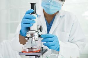 Asian scientist biochemist or microbiologist working research with a microscope in laboratory. For protect outbreak Coronavirus Covid19, bacteria and germs photo