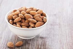 White Bowl With Almonds on Wood Background photo