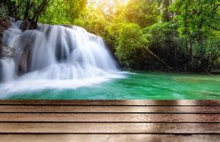 Wooden table top on fantastic waterfall in tropical forest photo