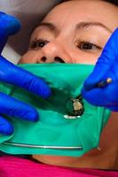 el dentista trata el diente del paciente con un dique de goma foto