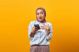 Retrato de mujer asiática sorprendida mediante teléfono móvil con la boca abierta foto