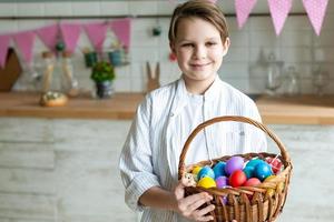 Cerca de niño sonriente con canasta de huevos de Pascua. foto