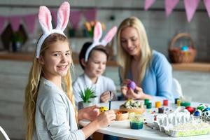 Close up, smiling girl looking into camera, painting easter egg. photo