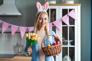 Beautiful blond woman holding flowers and Easter basket. photo