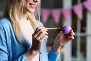 A woman is painting an Easter egg, close-up view. photo