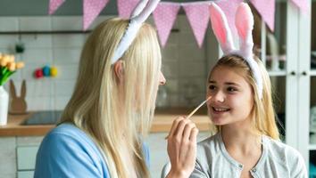 Mother and daughter with bunny ears headbands and painted Easter eggs at home photo