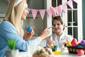 Mother and son with bunny ears headbands and painted Easter eggs at home photo