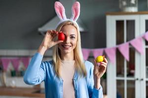 una mujer joven y feliz en las orejas del conejo se puso un huevo de pascua pintado en el ojo foto