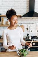 chica atractiva en la cocina hace una ensalada. el concepto de alimentación saludable foto