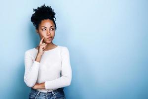 Pensive girl standing in the studio on a background of blue wall photo