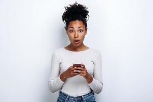 Surprised girl with a phone in the hands of the studio with a white background photo