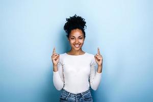 Positive, pretty, young girl showing thumbs up on a blue background photo