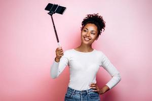 Pretty, smiling girl taking a selfie with a selfie stick photo