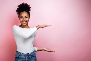 Beautiful girl holding something invisible isolated on gray background. Copy space photo