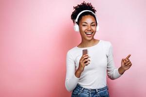 Charming, young girl happily listens to music, dances photo