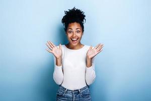 niña sorprendida y feliz de pie sobre un fondo azul foto