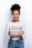 Estudiante sosteniendo libros en el estudio, sobre fondo de pared blanca foto