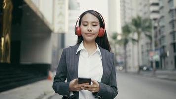 Asian businesswoman listening to music while walking in the street video