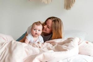 Beautiful young mother and newborn baby lying on the bed in the bedroom photo
