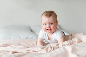 Retrato de un bebé gateando en la cama de su habitación foto