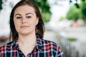 Beautiful girl, plus size looks straight into the camera, on a background of the city photo